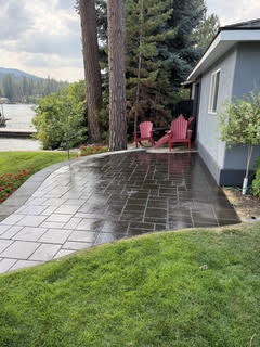 The same walkway after washing and sealing, the stone deep and even in colour, curving across the lawn toward the lakeshore.
